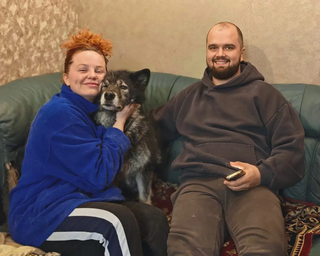 Ника обнимается с новой хозяйкой на диване, рядом сидит хозяин